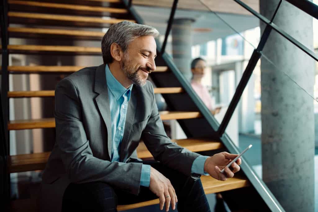 Photo of a happy business man using his mobile phone while relaxing