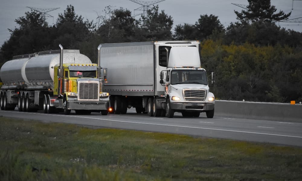 trailer-trucks-driving-road-surrounded-by-beautiful-green-trees